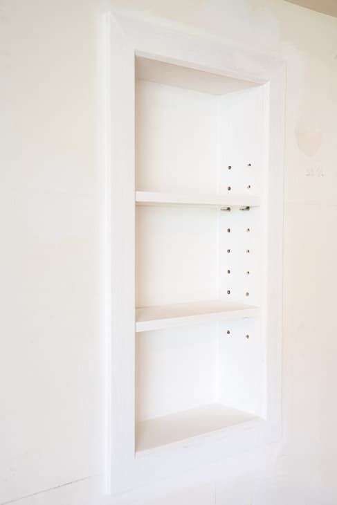 an empty white shelf in the corner of a room