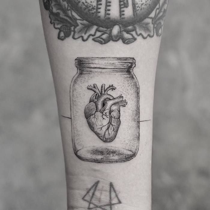 a heart in a jar tattoo on the left forearm and right arm with an arrow