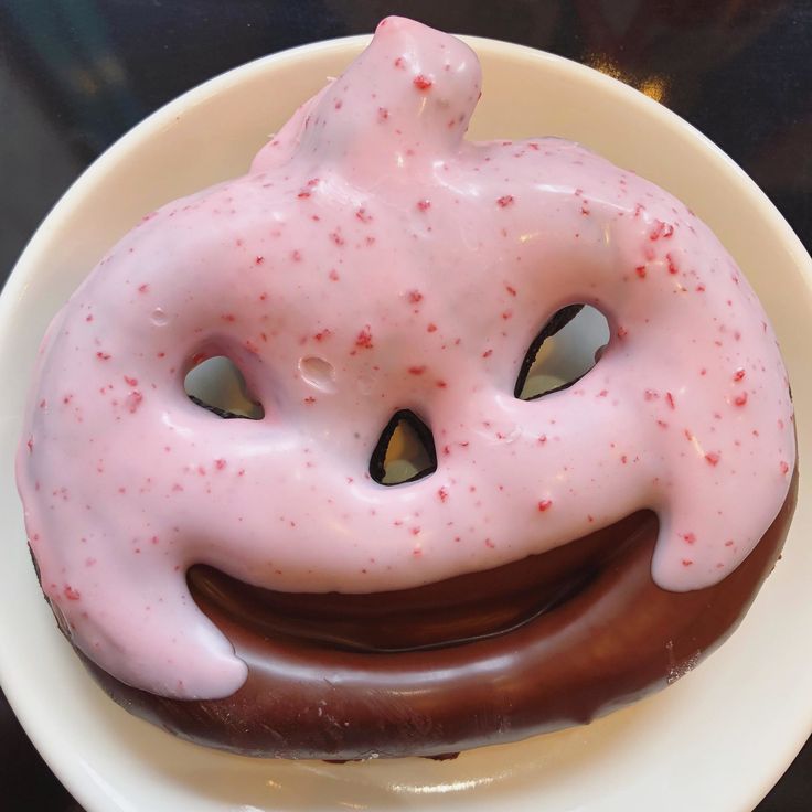 a donut with pink icing and sprinkles on it's face