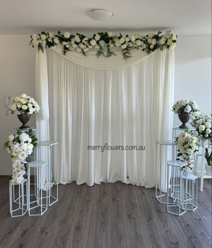 an image of a wedding setup with flowers on the wall and white draping