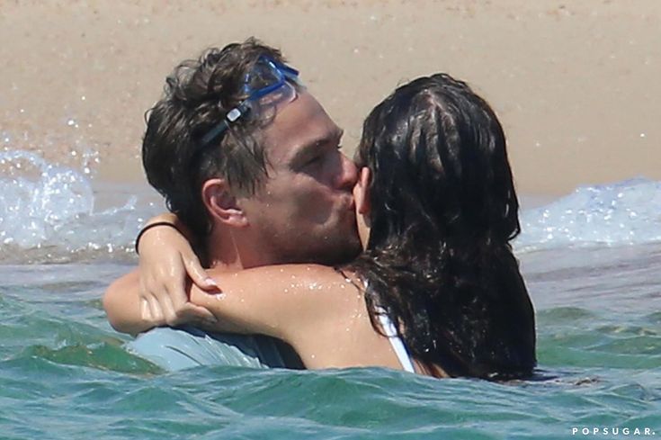 a man and woman kissing in the ocean