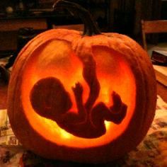 a carved pumpkin with the silhouette of a baby in it's stomach and feet