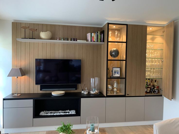 a living room with a large television on the wall and shelves filled with wine glasses