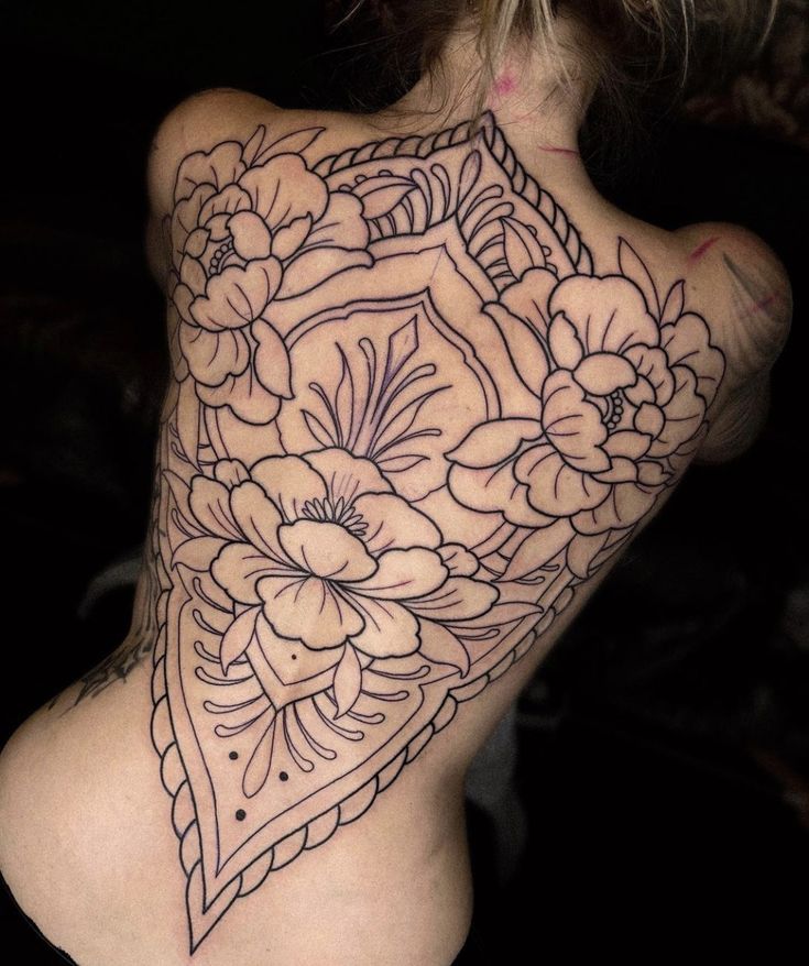 a woman's back tattoo with flowers on it