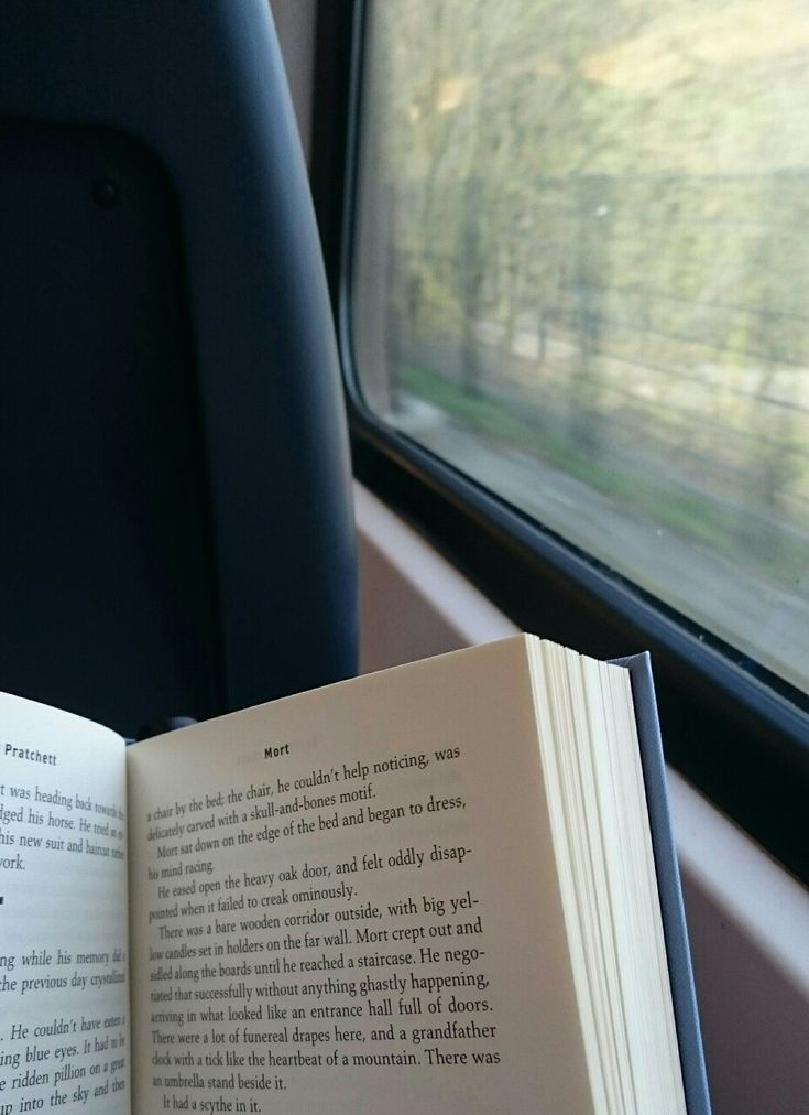 an open book sitting on top of a seat next to a window