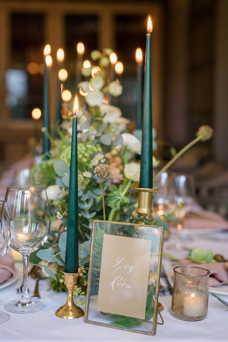 the table is set with candles, plates and glasses for dinner guests to sit at