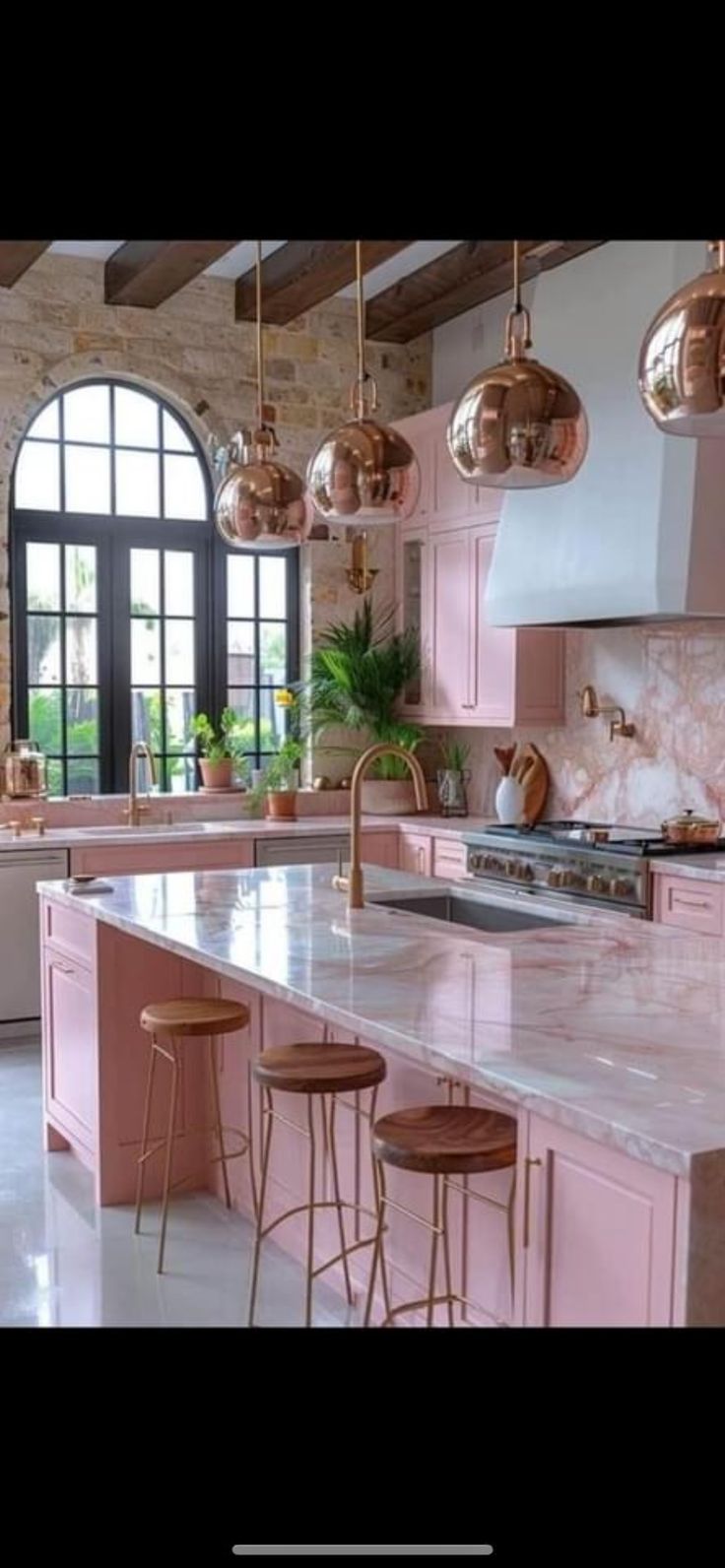 a large kitchen with pink cabinets and marble counter tops in front of an arched window