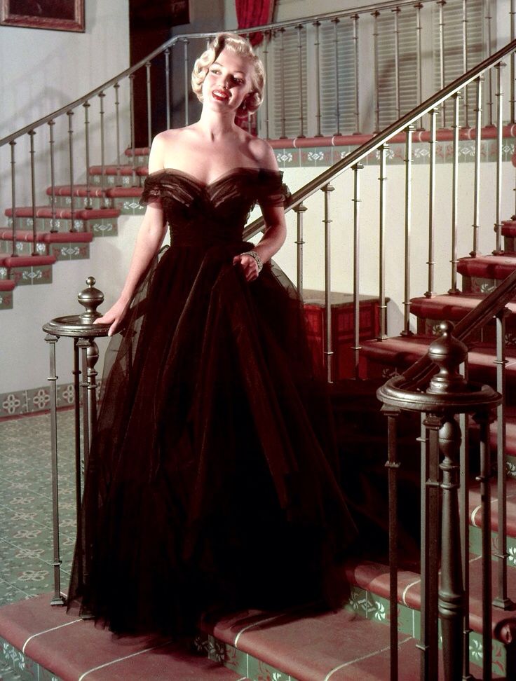 a woman in a black dress standing on some stairs