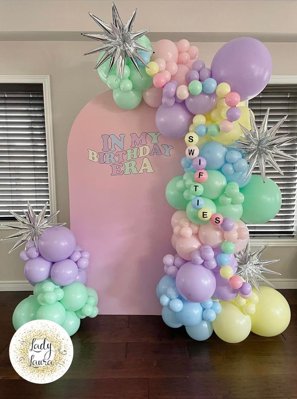 balloons and streamers are on the floor in front of a birthday arch