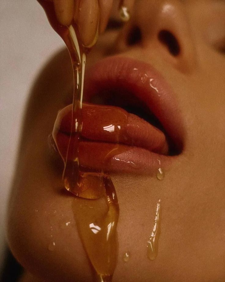 a woman is covered in caramel syrup while getting her lips brushed by someone else