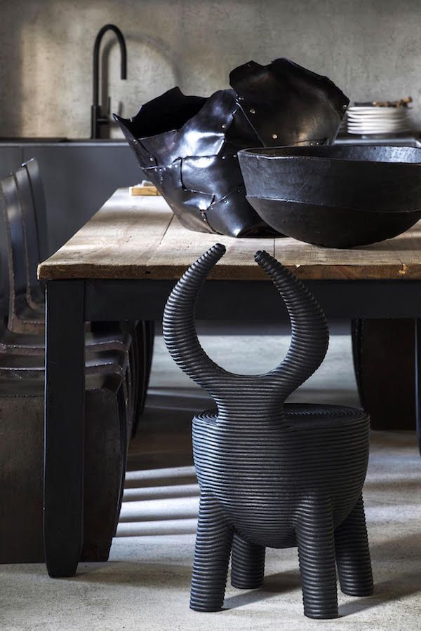 a black bowl sitting on top of a wooden table next to a metal animal sculpture