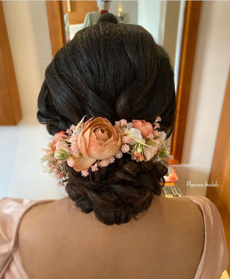 the back of a woman's head with flowers in her hair and an updo