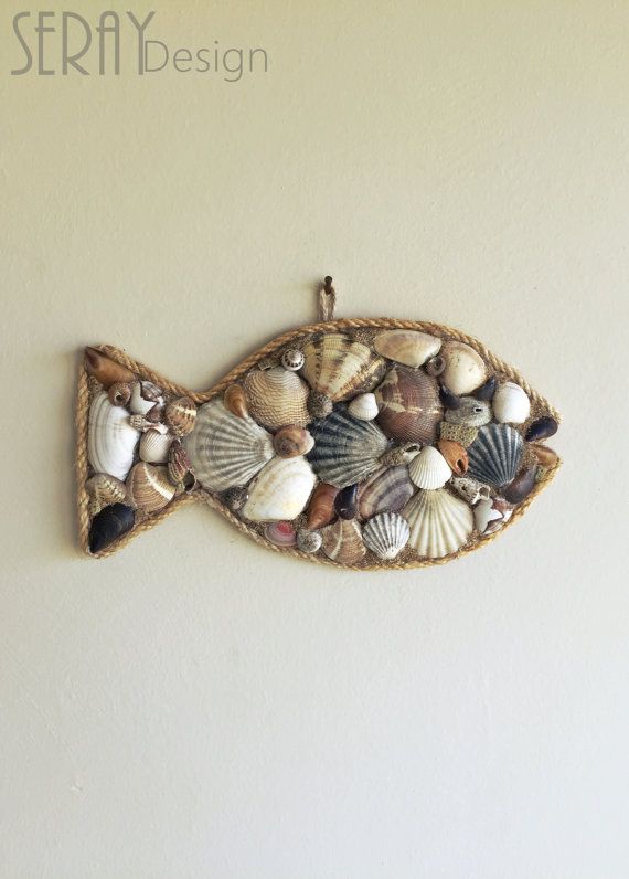 a fish made out of sea shells hanging on a wall