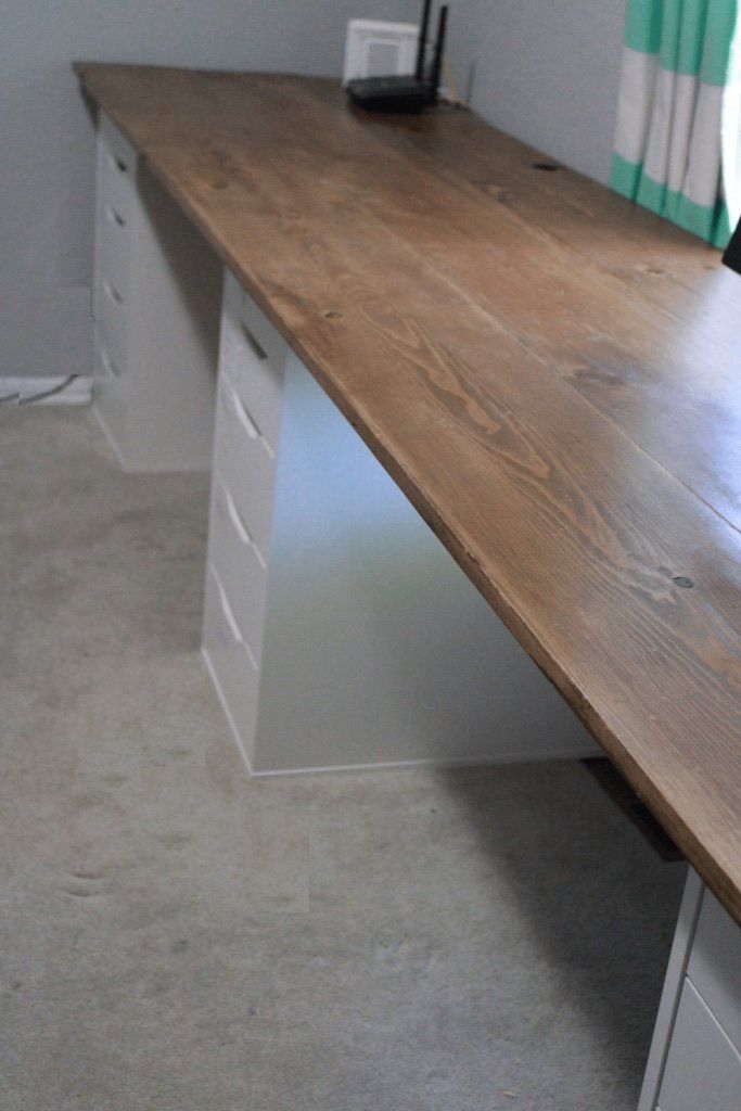 a wooden desk sitting in the middle of a room with two drawers and a phone on top of it