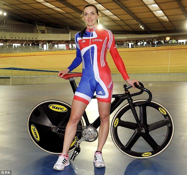 a woman standing next to a bike in an indoor arena