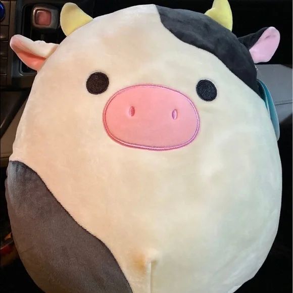 a close up of a stuffed animal on a car steering wheel cover with a cow's face