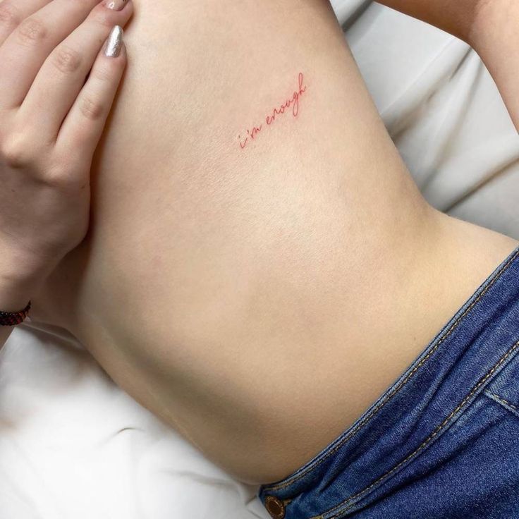 a woman laying on top of a bed with her stomach covered in red ink and writing