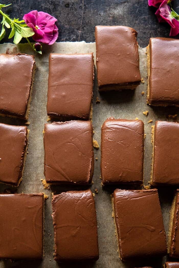 chocolate brownies on a baking sheet with flowers in the background and one cut into squares