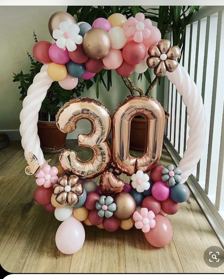 a balloon arch with the number thirty nine surrounded by flowers and balloons on a wooden floor