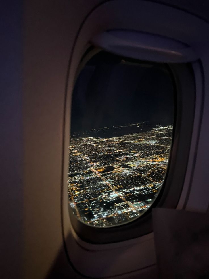 an airplane window looking out at the city lights