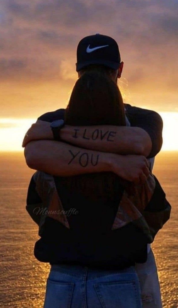 two people with their arms wrapped around each other and the sun setting in the background