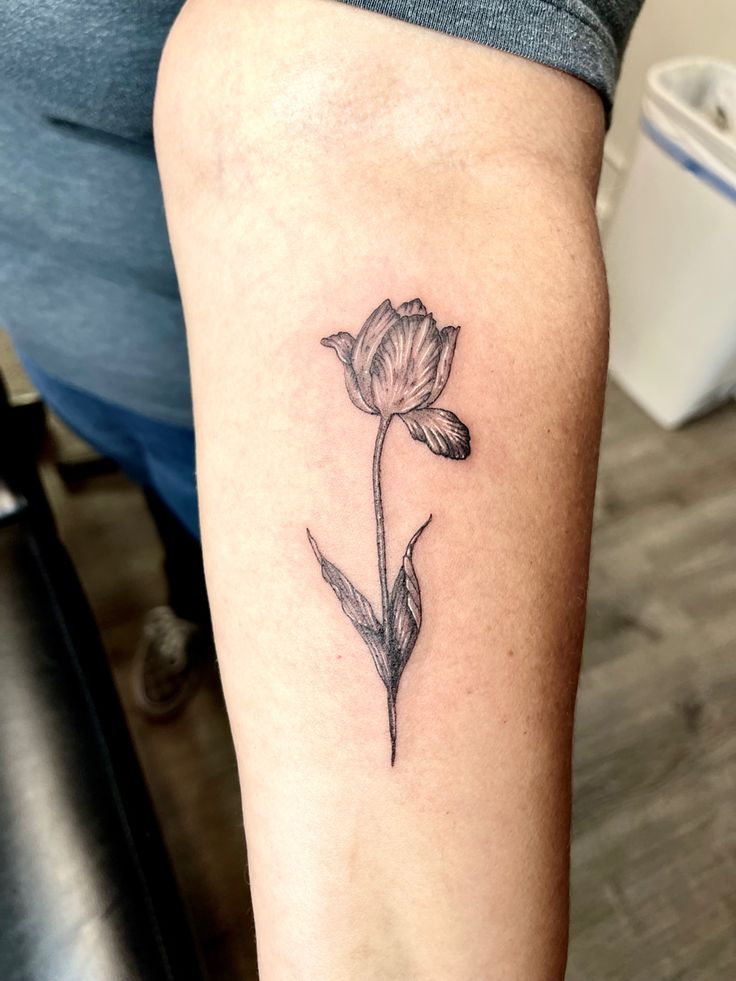 a woman's arm with a single flower tattoo on the left side of her leg