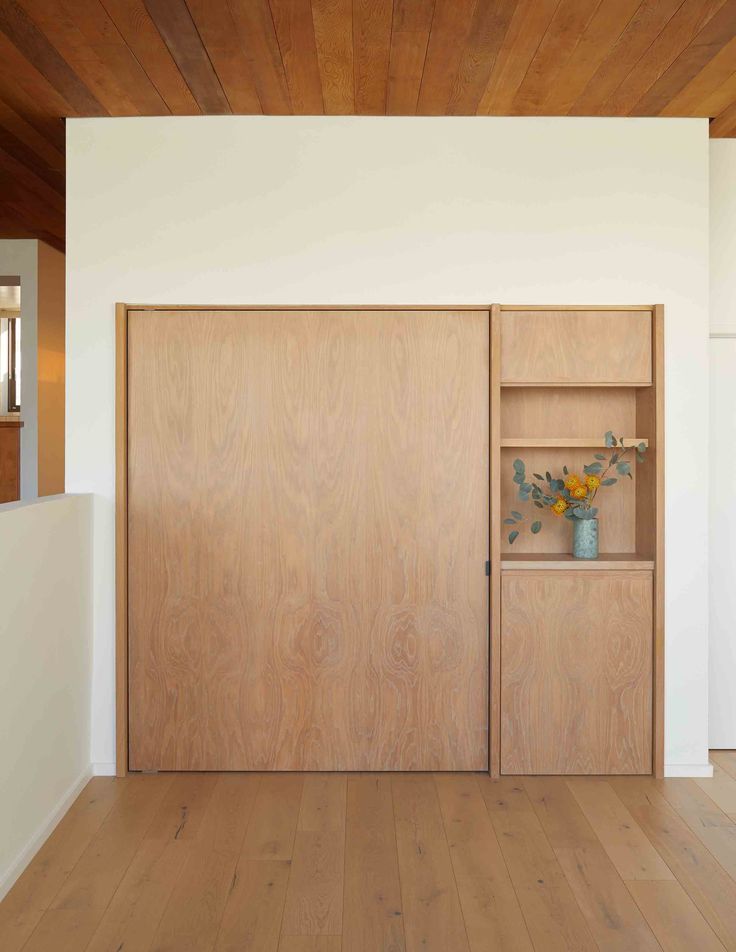 an empty room with wooden doors and shelves on the wall next to a white wall