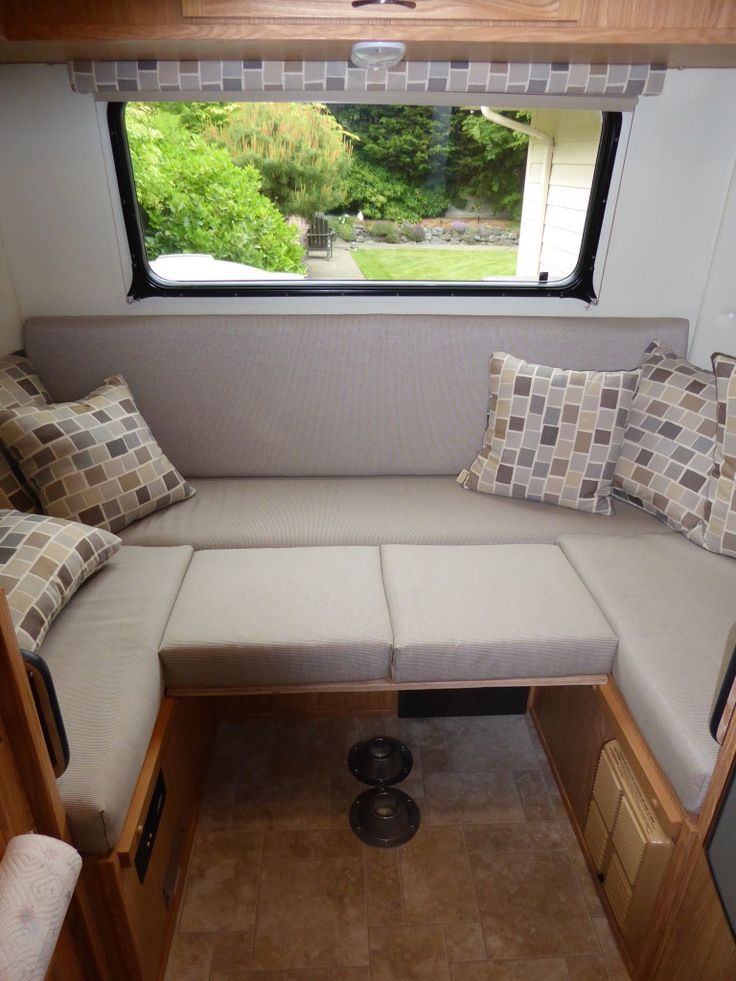 the inside of a small camper with couches and pillows on it's side