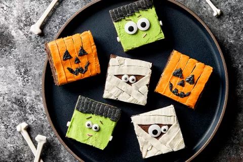 halloween treats made to look like tombstones with eyes and noses on a black plate