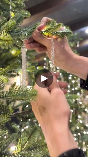 two hands are decorating a christmas tree