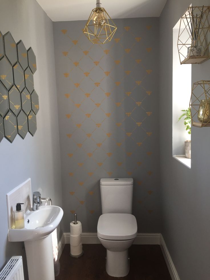 a white toilet sitting in a bathroom next to a sink under a light hanging from a ceiling fan