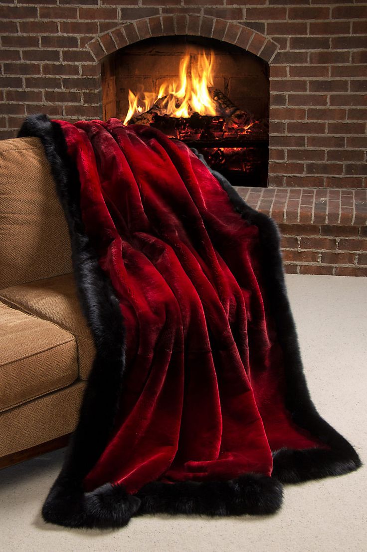 a red and black blanket sitting in front of a fire place