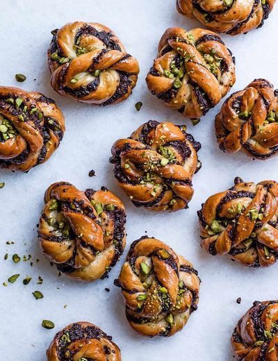 many small pastries with nuts on top of them and sprinkled with pistachio