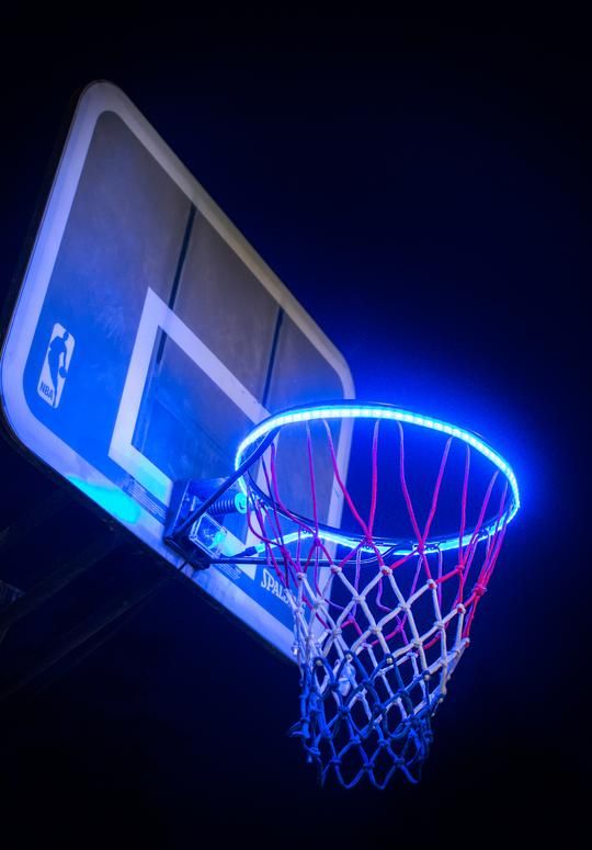 a basketball hoop lit up in the dark with neon lights and a blue backboard