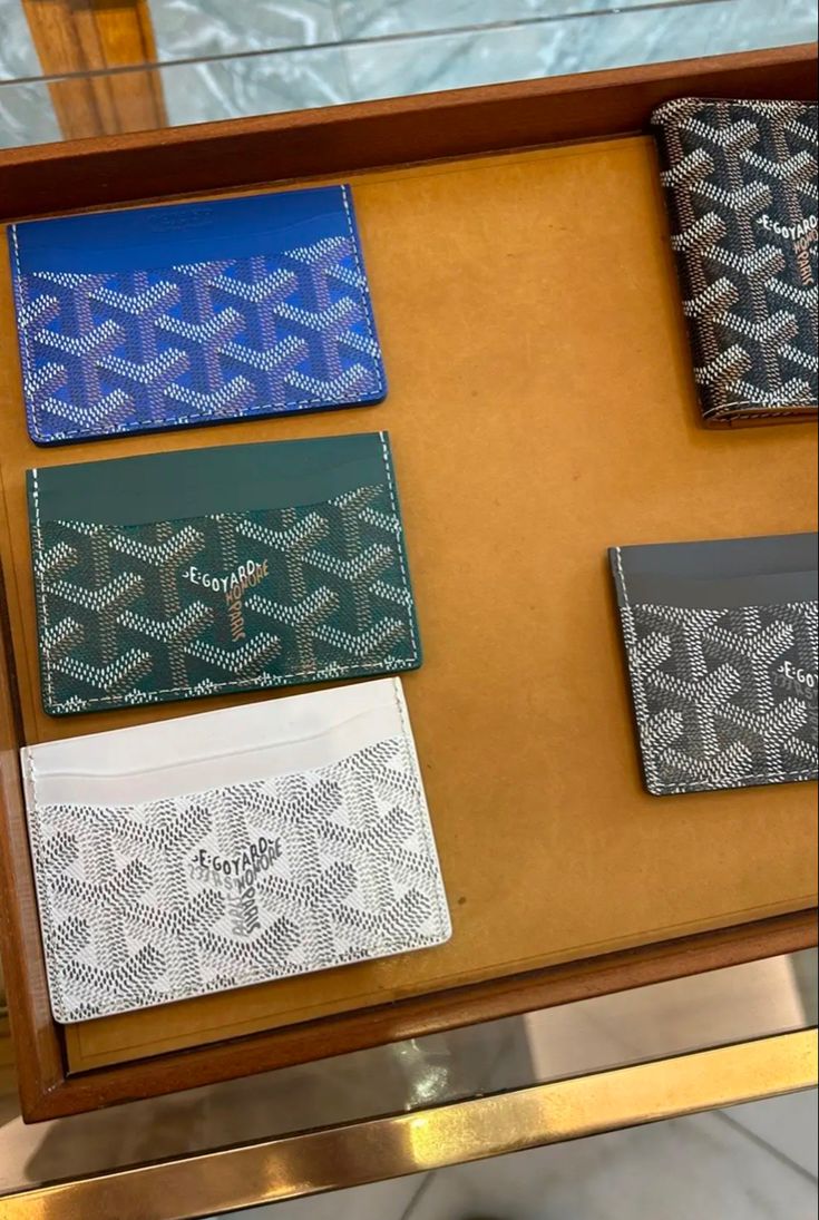 four different types of wallets on display in a store window, one is blue and the other has silver