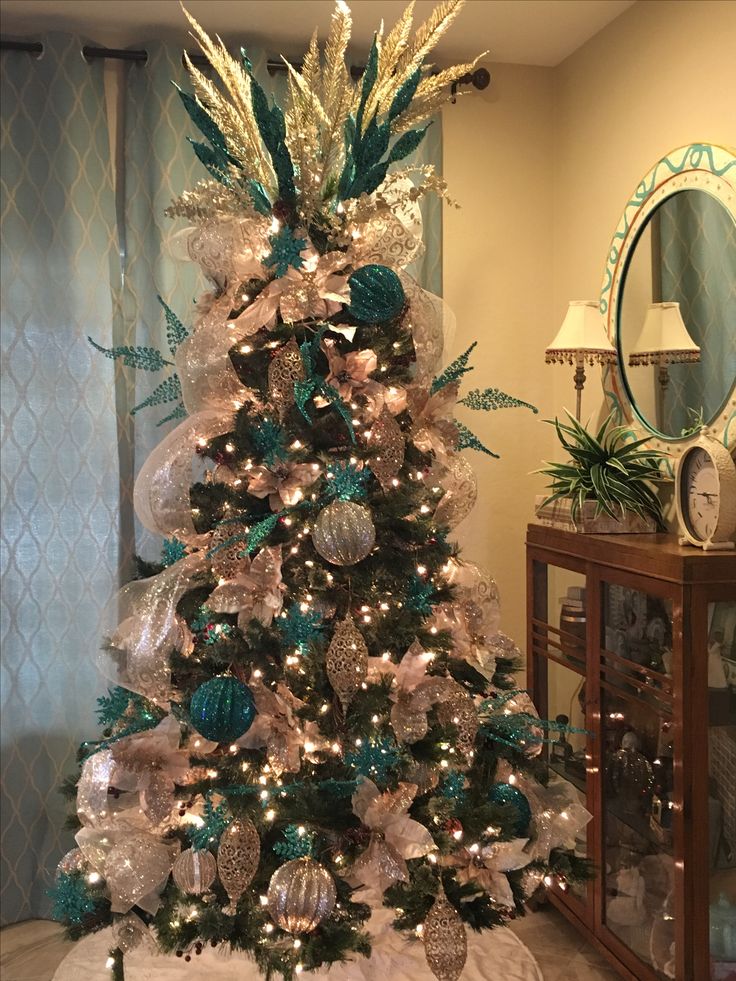 a christmas tree decorated with blue and white ornaments in a living room next to a mirror