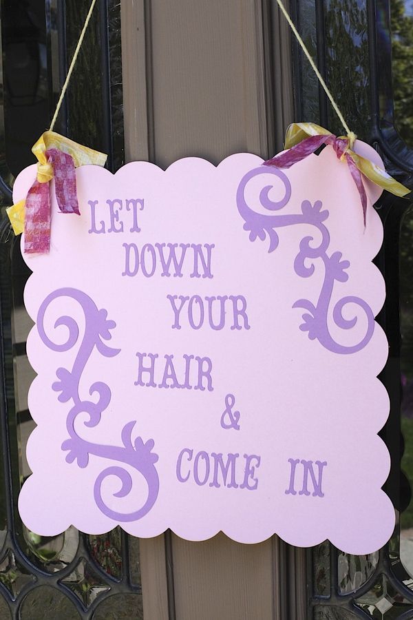 a sign hanging from the side of a door that says let down your hair and come in