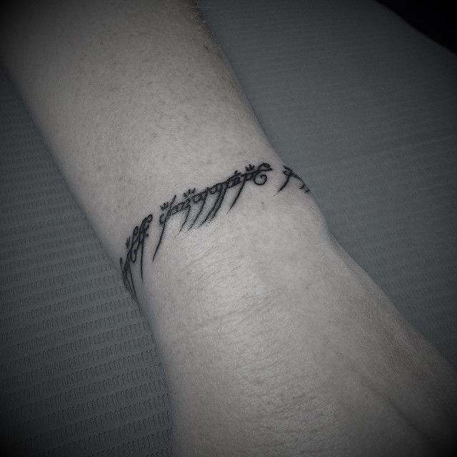 a black and white photo of a wrist tattoo