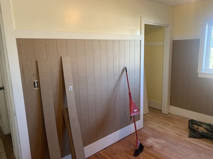 an empty room with wooden paneling and mop on the floor next to it