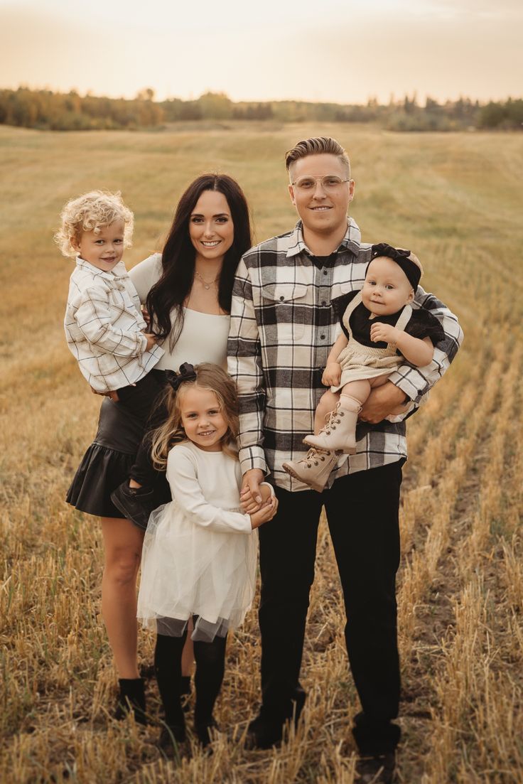 a family poses for a photo in a field with their two children and one adult