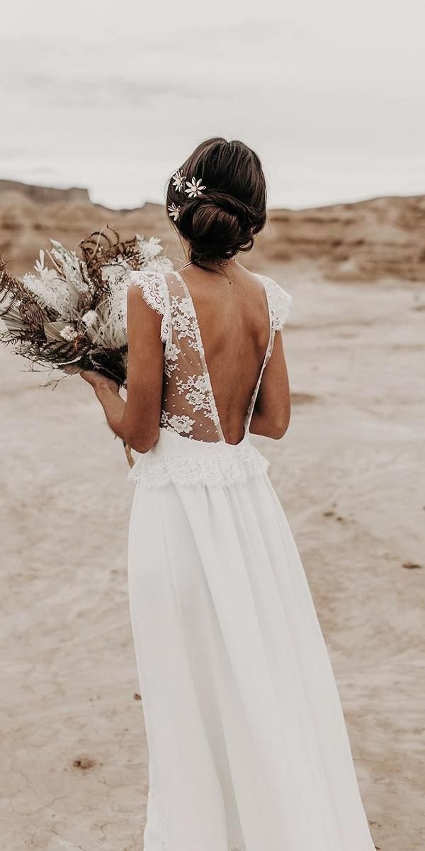 a woman in a white dress is standing on the beach with her back to the camera