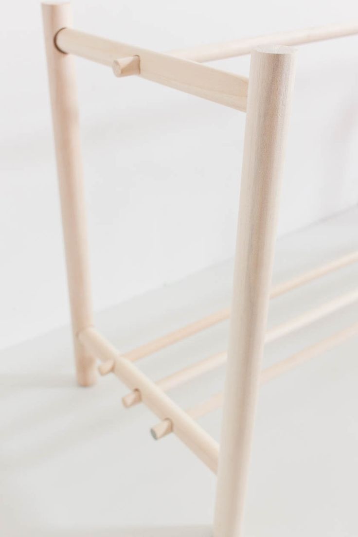 a close up of a white bed frame with wooden posts and hooks on the sides