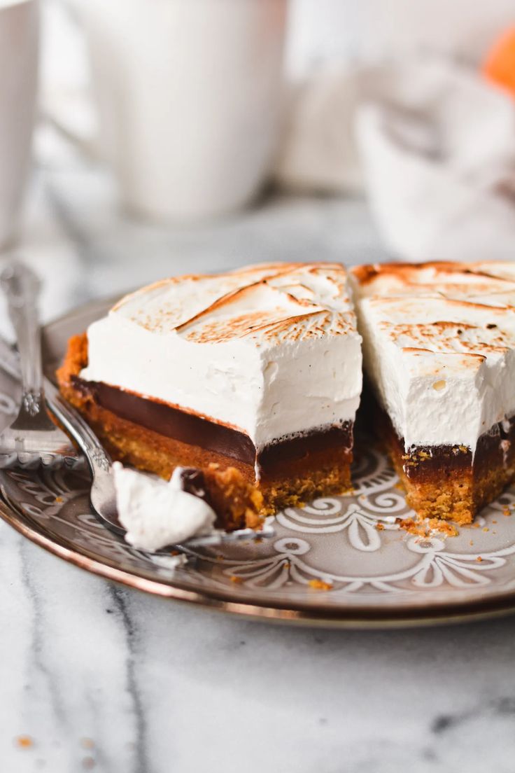 a piece of cake on a plate with a fork and cup in the back ground