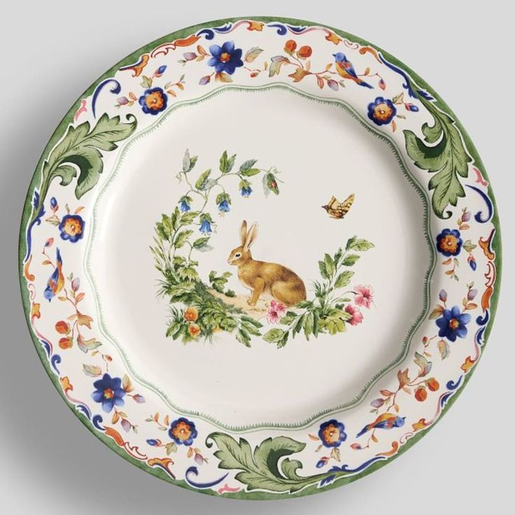 a plate with an image of a rabbit and flowers on the rim, painted in green