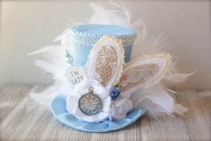 a blue hat with white feathers and a clock on it's side, sitting on top of a table