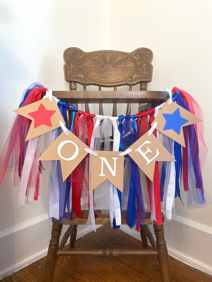 a wooden chair with red, white and blue streamers on it that say one