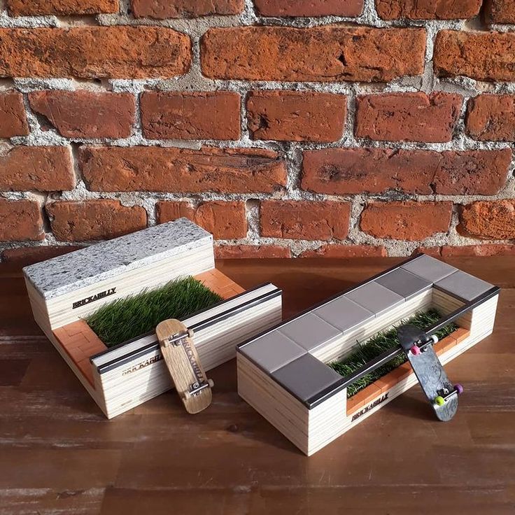 two wooden boxes with plants in them sitting on a table next to a brick wall