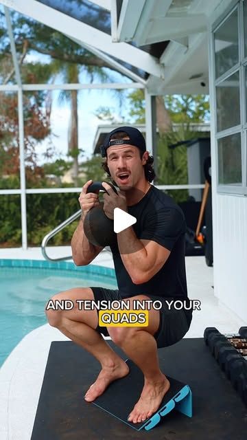 a man squatting on a mat in front of a swimming pool holding a water hose