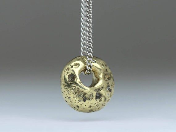 This solid gold sand cast pendant is made from 14ct yellow gold and is reminiscent of the ancient Cornish standing stones. These pendants are cast in sand from Cornish beaches – giving every piece a totally unique texture. Hanging on a 9ct white gold curb chain, this is a delicate and subtle pendant which wears well for any occasion.An intricate process of handcrafting ensures that every piece is beautifully bespoke.  Every item is individually hallmarked and bears Justin’s maker’s mark that gua Ancient Style Yellow Gold Brass Jewelry, Symbolic Electroformed Gold Jewelry, Gold Medallion Hand Cast Jewelry, Ancient Etched Gold Jewelry, Gold Medallion Jewelry Hand Cast, Gold Hand Cast Amulet Jewelry, Ancient Style Gold Brass Jewelry, Ancient Gold Jewelry For Ceremonial Occasion, Ancient Style Gold Jewelry For Ceremonial Occasion