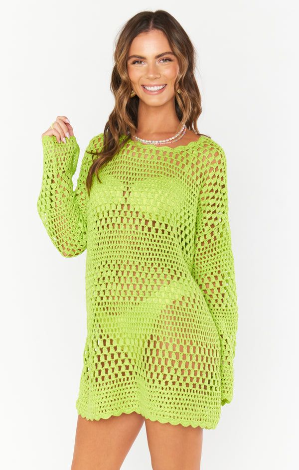 a woman wearing a neon green sweater with holes on the side and long sleeves, posing for